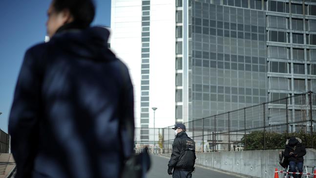 FILE - In this Jan. 11, 2019, file photo, a security official, center, stands guard in front of Tokyo Detention Center, where former Nissan chairman Carlos Ghosn is detained, in Tokyo.{ } (AP Photo/Eugene Hoshiko, File)