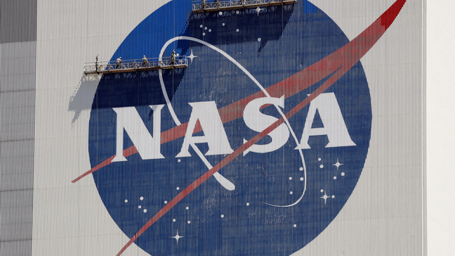 FILE - Workers on scaffolding repaint the NASA logo near the top of the Vehicle Assembly Building at the Kennedy Space Center in Cape Canaveral, Fla., May 20, 2020. (AP Photo/John Raoux, File)